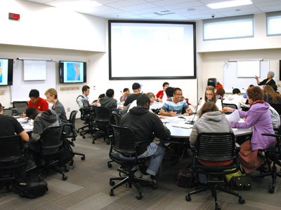 Deborah Rifenbary, UNM College of Education associate dean and coordinator of the STARS program, looks over the shoulder of Austrian schoolchildren as they create posters depicting New Mexico.